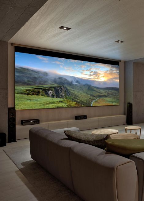 A home theater room featuring a large screen displaying a misty, green landscape with comfortable seating.
