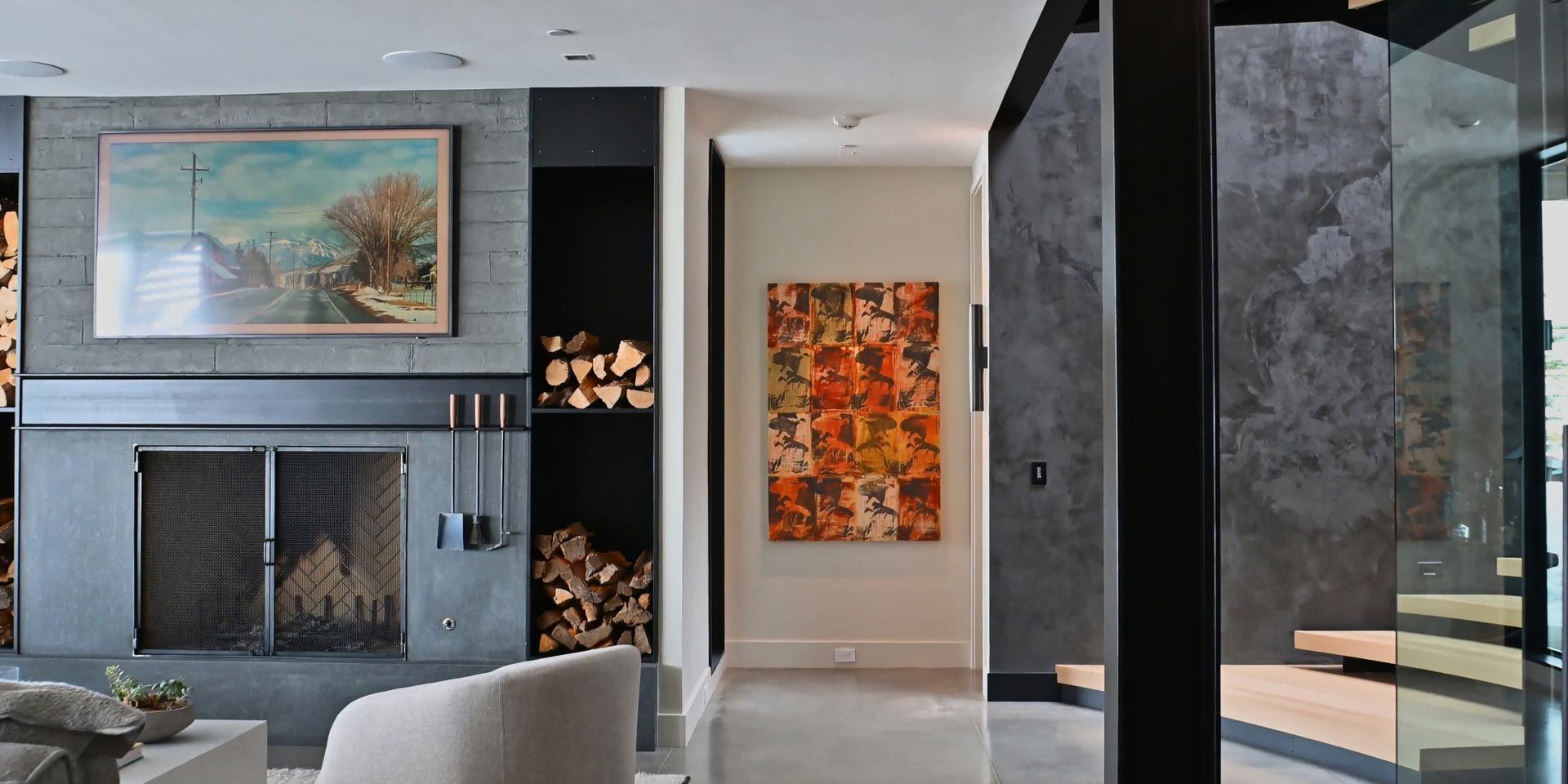 A stylish interior with a fireplace, log storage, and colorful artwork on the wall.