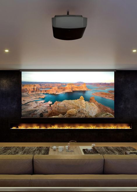 A modern home theater with a large projection screen, showcasing a landscape image above a sleek fireplace.