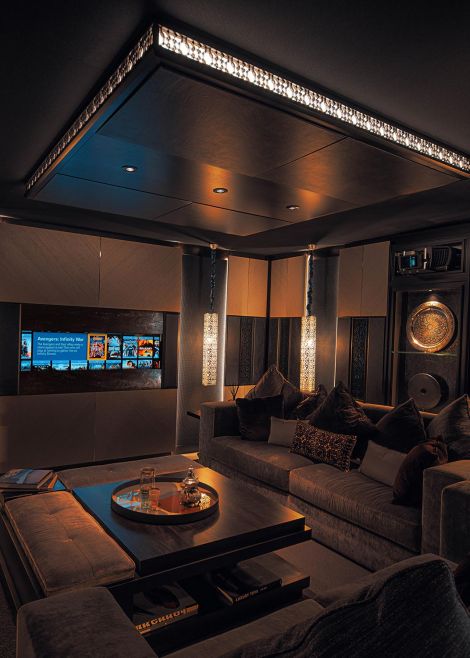 A cozy home theater with luxurious seating, a large screen displaying a movie interface, and elegant lighting fixtures.