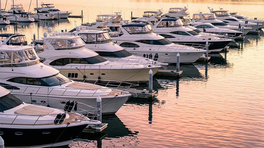 Row of white luxury yachts moored at a marina during sunset