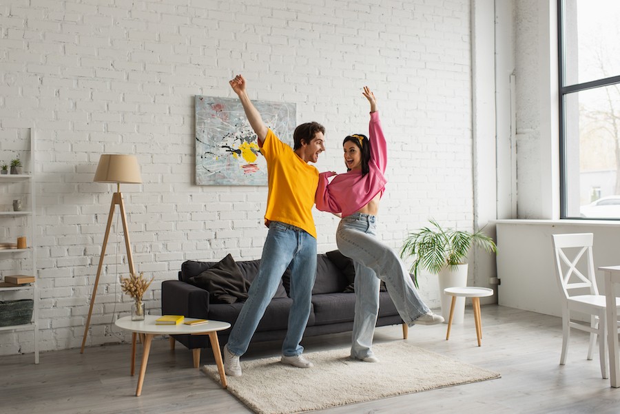 A young couple dancing to their whole-home audio system.