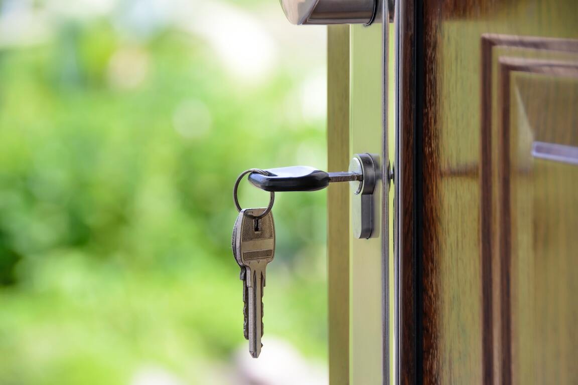 A key on dangles from the front lock of an open residential door. 