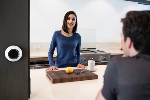 A man and woman standing in a kitchen using voice-controlled home automation.