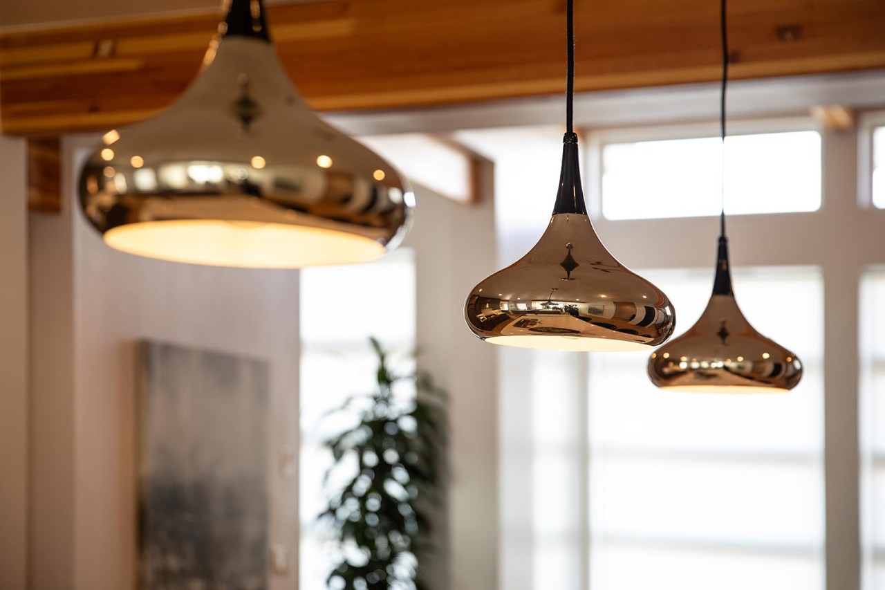 Trio of modern metallic pendant lights hanging in a sunlit interior