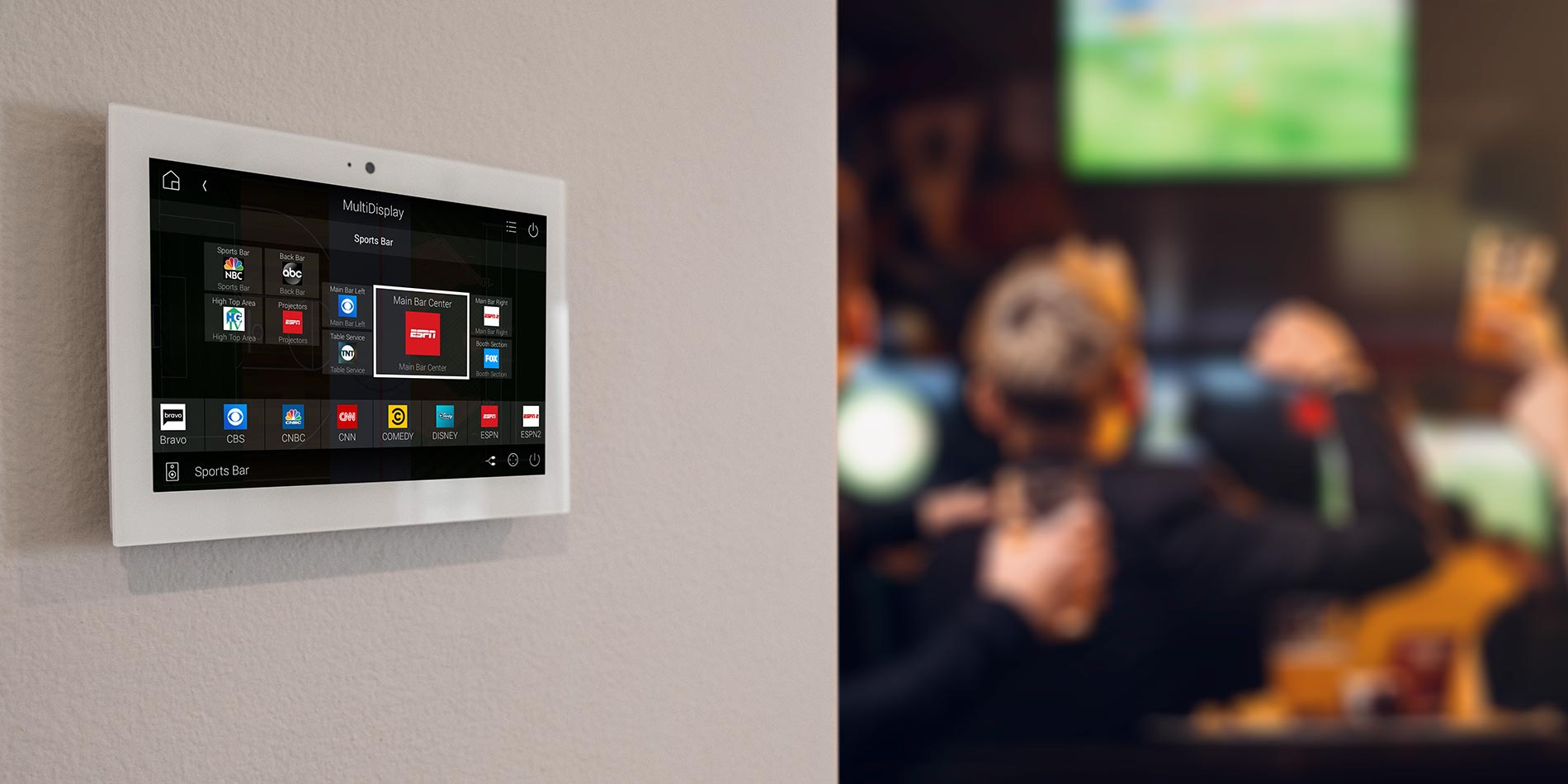 Wall-mounted Control4 smart control panel interface in a sports bar setting