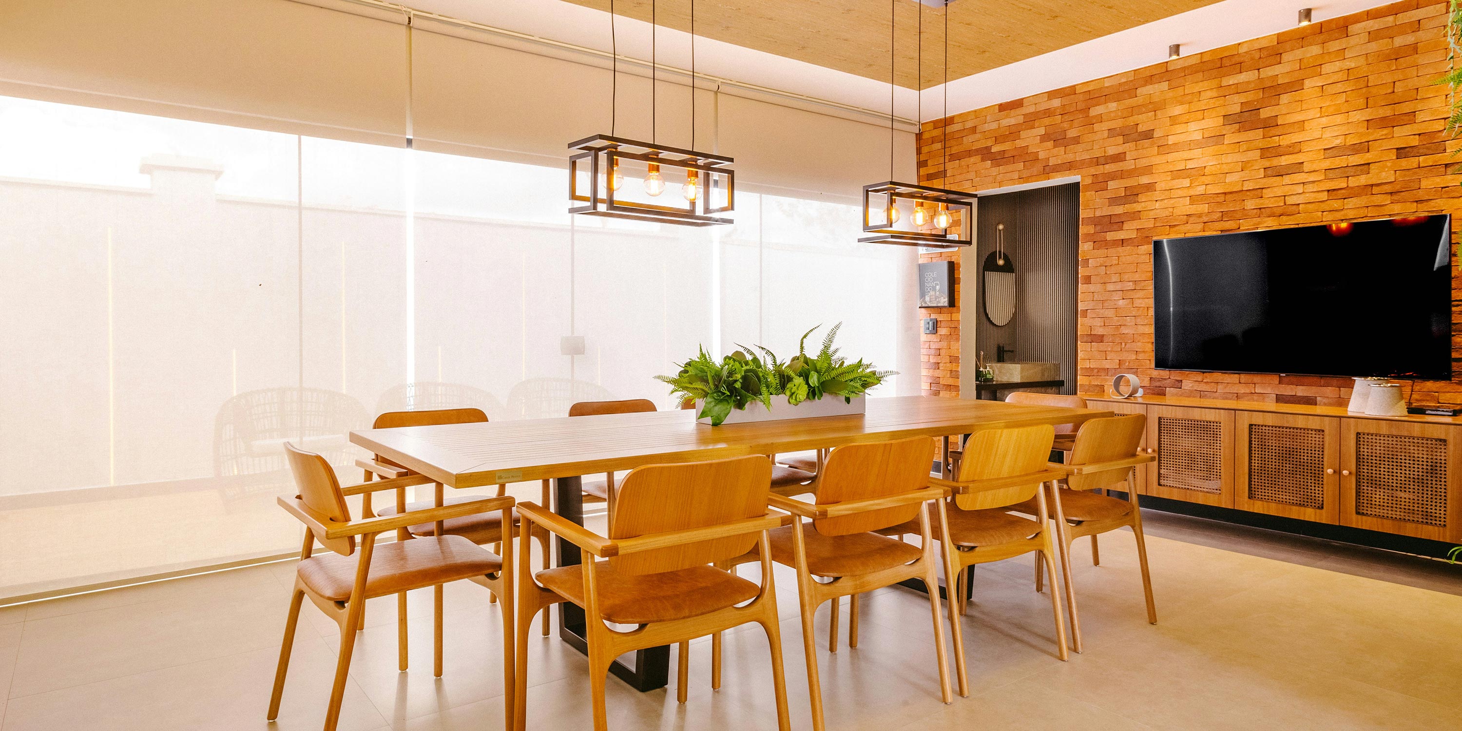 Sunlit dining room with brick accent wall, wooden furniture, and hanging lights