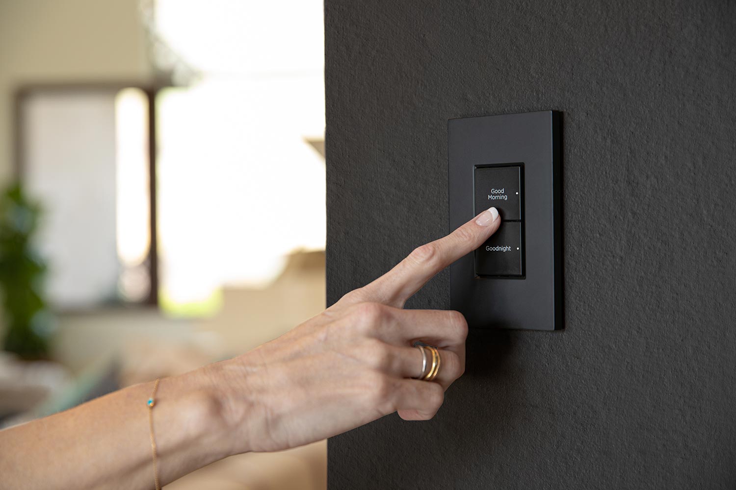 Hand pressing a black wall switch with morning and night buttons