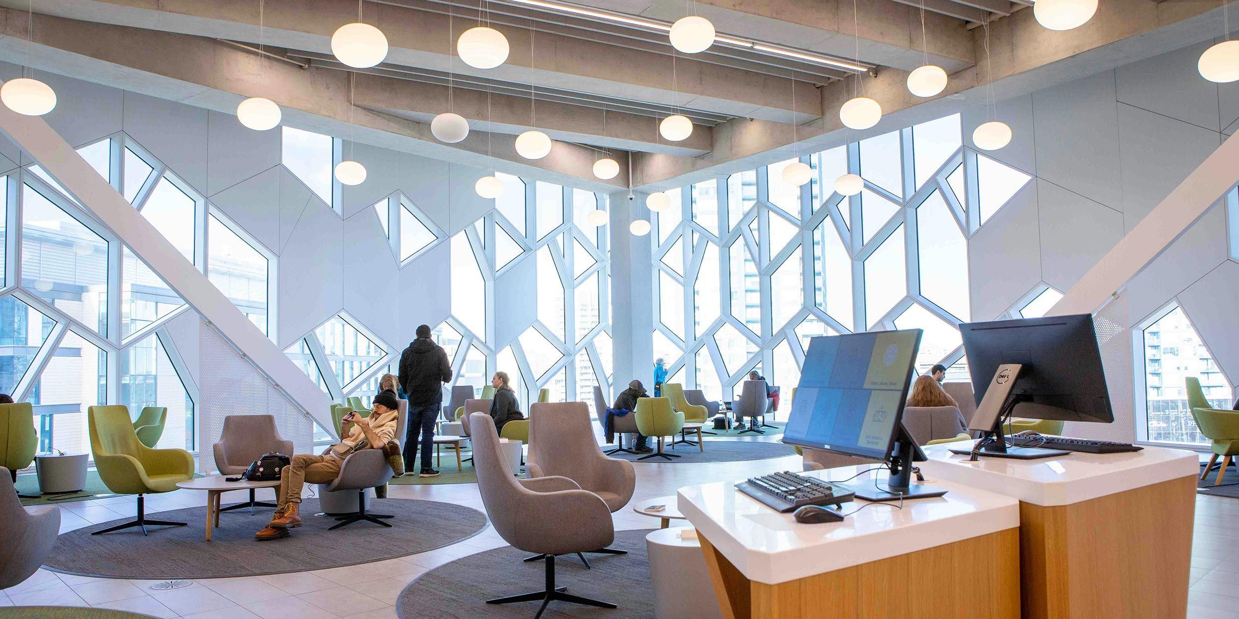 Modern office lounge with geometric windows, round lights, and people working